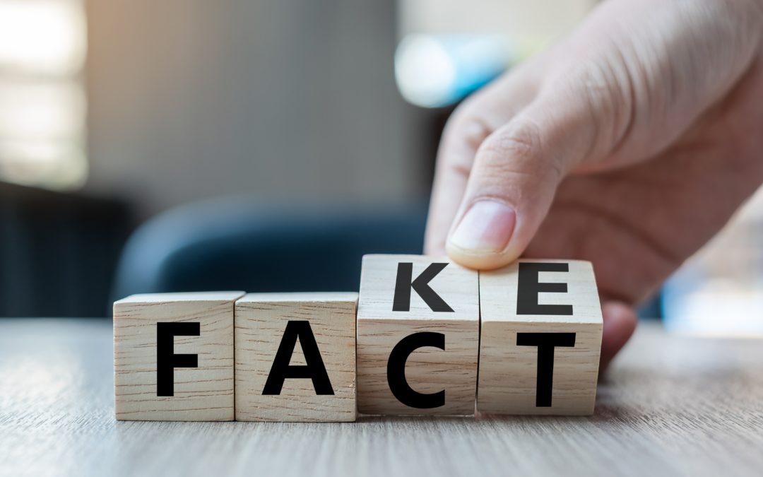 Fact vs Fake News: Business man hand holding wooden cube with flip over block FAKE